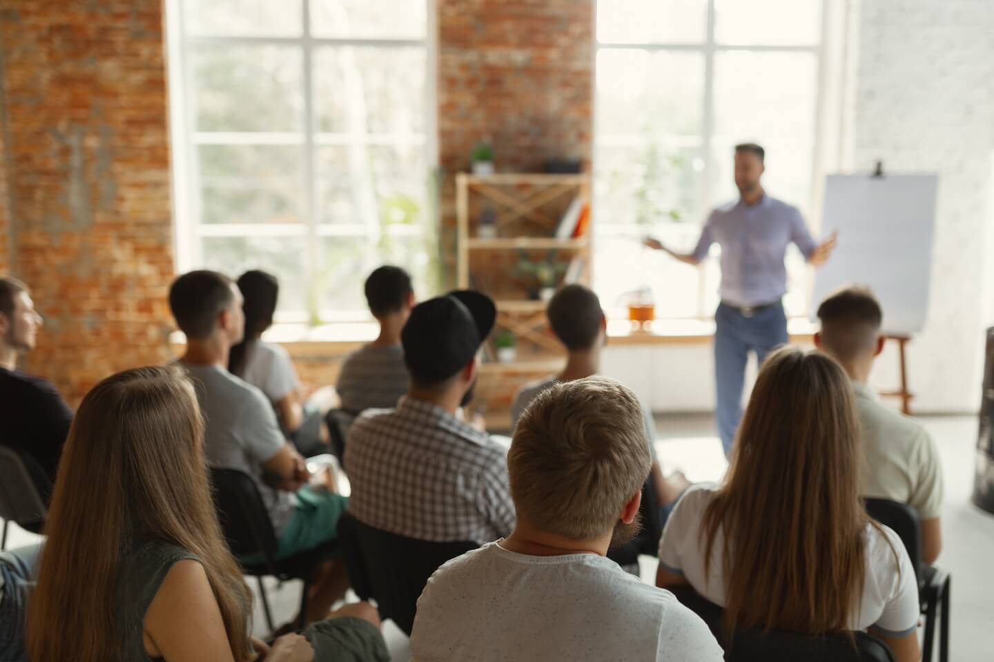 Conférence d’un homme devant plusieurs salariés assis le suns à côté des autres